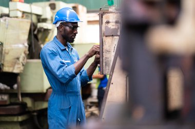 Siyah Erkek Mühendis Fabrika 'da makine üzerinde çalışıyor. Makinenin durumunu kontrol eden siyah adam mühendisi. Fabrika makinelerinin bakım ve onarımı. Amerikan Afrikalıları.