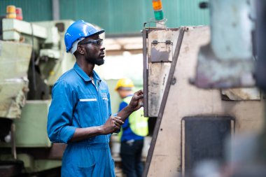 Siyah Erkek Mühendis Fabrika 'da makine üzerinde çalışıyor. Makinenin durumunu kontrol eden siyah adam mühendisi. Fabrika makinelerinin bakım ve onarımı. Amerikan Afrikalıları.