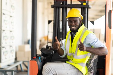 Depoda çalışan işçi sürücü forklift. Depoda forkliftle kart kutuları istifleyen bir depo çalışanı. Afrikalı Amerikalı siyahiler.