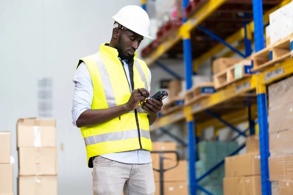 middle aged African American warehouse worker preparing a shipment in large warehouse distribution centre