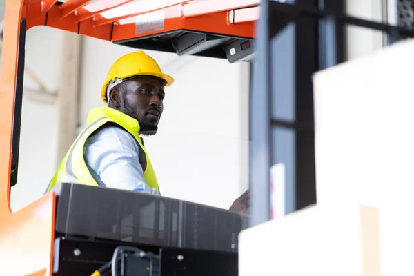 Warehouse man worker driver forklift. warehouse worker driver stacking card boxes by forklift in warehouse store. African American black people.