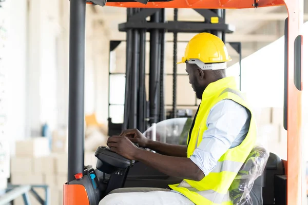 Warehouse man worker driver forklift. warehouse worker driver stacking card boxes by forklift in warehouse store. African American black people.