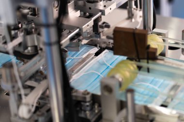 Makineler steril bir fabrikada maske üretmek için çalışıyor. Tıbbi maske üretimi. bir maske üretme süreci