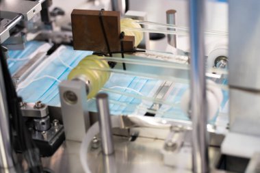 Makineler steril bir fabrikada maske üretmek için çalışıyor. Tıbbi maske üretimi. bir maske üretme süreci