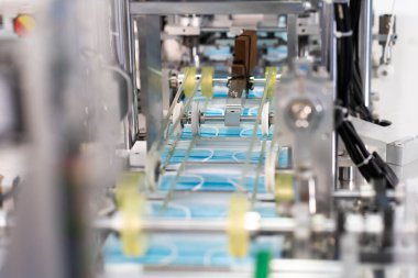 Makineler steril bir fabrikada maske üretmek için çalışıyor. Tıbbi maske üretimi. bir maske üretme süreci