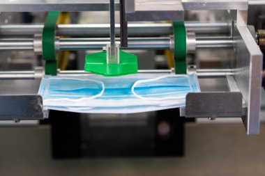 Makineler steril bir fabrikada maske üretmek için çalışıyor. Tıbbi maske üretimi. bir maske üretme süreci