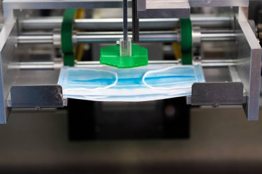 Makineler steril bir fabrikada maske üretmek için çalışıyor. Tıbbi maske üretimi. bir maske üretme süreci