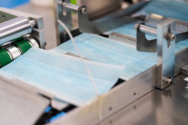 Makineler steril bir fabrikada maske üretmek için çalışıyor. Tıbbi maske üretimi. bir maske üretme süreci