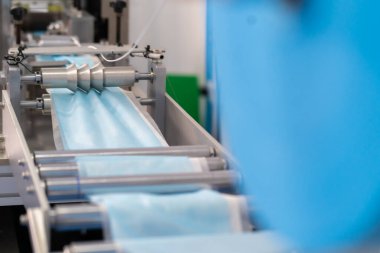 Makineler steril bir fabrikada maske üretmek için çalışıyor. Tıbbi maske üretimi. bir maske üretme süreci