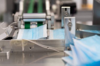 Makineler steril bir fabrikada maske üretmek için çalışıyor. Tıbbi maske üretimi. bir maske üretme süreci