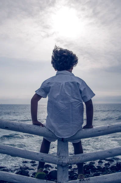 Gyermek ül a kerítésen, tengerre néző — Stock Fotó
