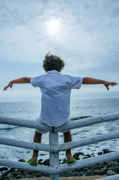 Bambino rilassarsi sulla spiaggia aprendo le braccia sullo sfondo del mare e del cielo — Foto Stock