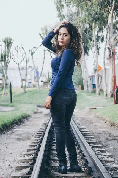 Junges sexy Mädchen mit langen Haaren in Jeans auf einer Eisenbahn. Verführerische Frau blickt in Kamera — Stockfoto