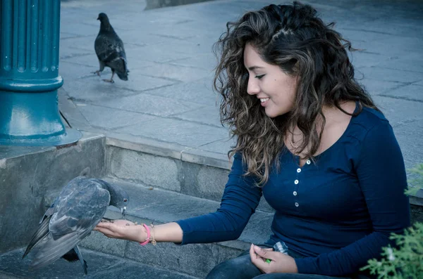 A smiling woman feeding a pigeon from her hand — Stock Photo, Image
