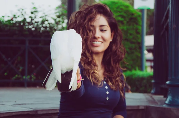 A smiling woman feeding a pigeon from her hand — Stock Photo, Image