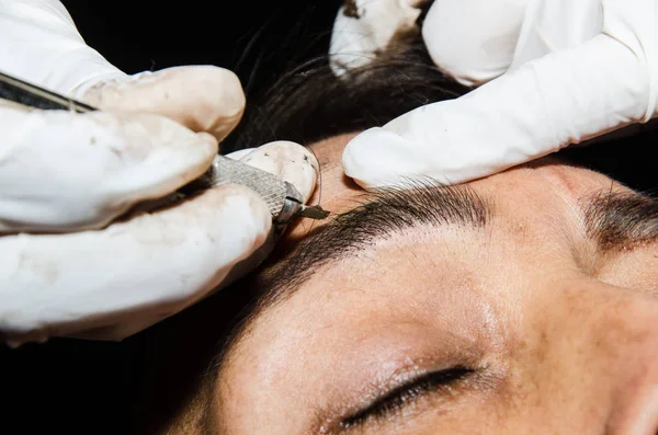 Permanent makeup tattooing of eyebrows. Cosmetologist applying permanent make up on eyebrows