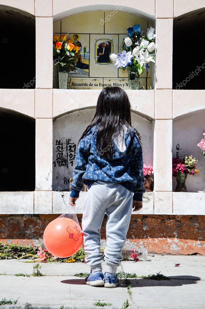Girl from behind looking at the grave of a loved one