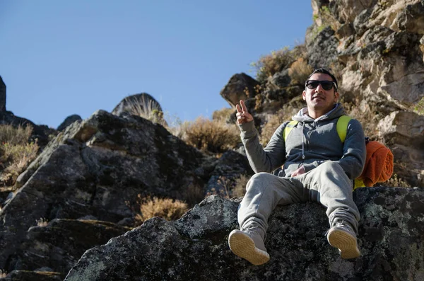 Homem viajante sentado em uma rocha posando para a câmera em Marcahuasi — Fotografia de Stock