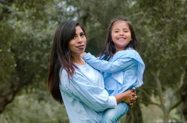 Mère portant sa fille mignonne et souriante dans le parc — Photo