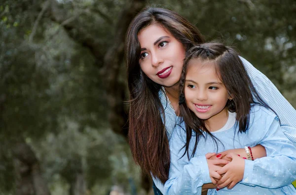 Madre cargando a su linda y sonriente hija en el parque — Foto de Stock