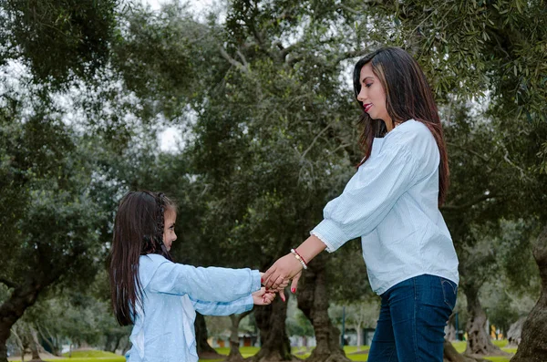 Madre e hija pequeña tomadas de la mano divirtiéndose en un parque — Foto de Stock