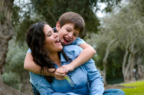 Niño abrazando a su madre sonriendo en una tarde de otoño — Foto de Stock