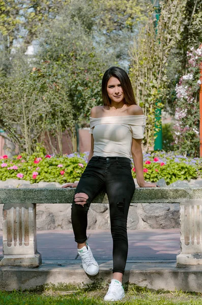 Glückliche junge Frau sitzt auf Bank im Stadtpark stilvolles Mode-Modell — Stockfoto