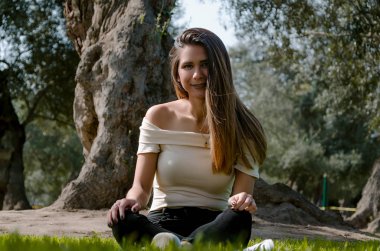 Bir parkta bir ağacın altında oturup şık neşeli esmer