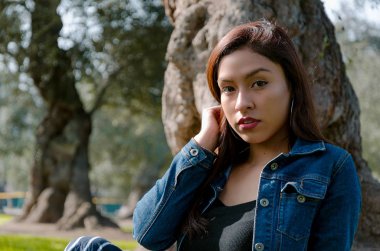 Çimenlikte oturan çekici, Genç ve çekici esmer Bayan portresi.