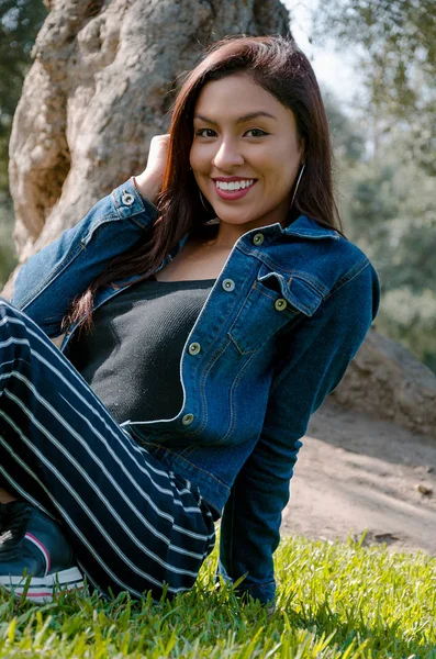 Retrato de una atractiva, joven y atractiva morena sentada en el césped . — Foto de Stock