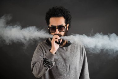 Bir mod tutarak Vaping adam. Buhar bulutu. Siyah arka plan. Vaping çok duman ile elektronik sigara.