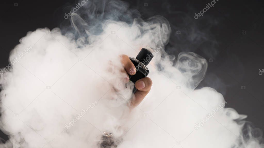 Hand of man soars on the smoke with mod in a black background.