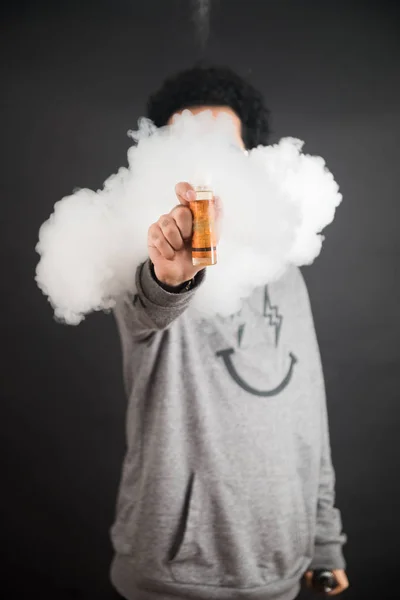 Concepto Vape. Nubes de humo y botellas líquidas de vapor sobre fondo oscuro . — Foto de Stock