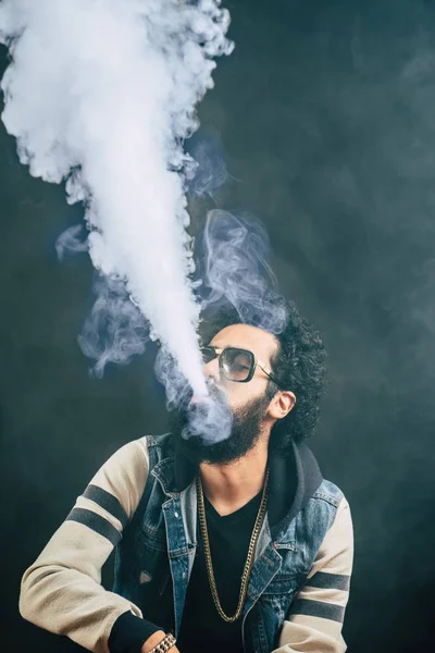 Young man with beard vaping an electronic cigarette upwards. Vaper hipster smoke vaporizer. — Stock Photo, Image