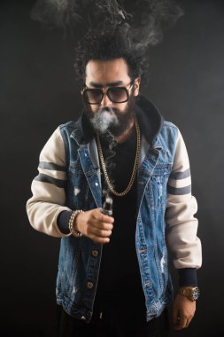 Sakal ve güneş gözlüğü vaping elektronik sigara olan genç adam. Duman buharlaştırıcı