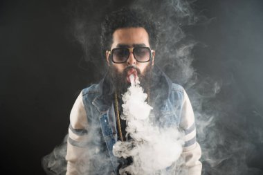 Bir mod tutarak Vaping adam. Buhar bulutu. Siyah arka plan. Vaping çok duman ile elektronik sigara.