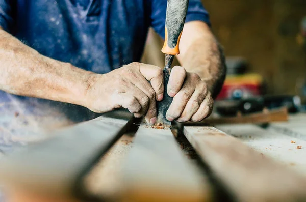 Carpintero profesional en el trabajo, está tallando madera usando una herramienta de carpintería, manos cerca, carpintería y concepto de artesanía —  Fotos de Stock