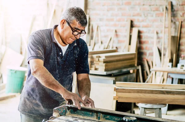 Carpintero cortando tabla de madera en su taller —  Fotos de Stock