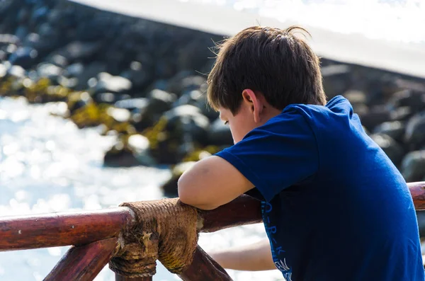 Un ragazzo che guarda il mare con le spalle alla macchina fotografica . — Foto Stock