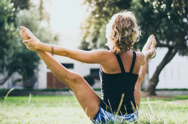 여자 청바지 블랙 탱크 탑 공원에 upavistha konasana 요가 포즈를 하 고 있는. — 스톡 사진