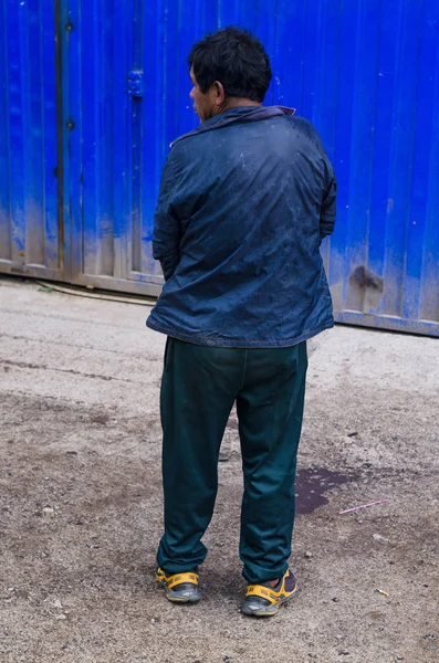 Rückansicht eines Mannes, der auf der Straße gegen eine Mauer pinkelt — Stockfoto