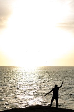 Siluet balıkçı denize net atma köprünün kenarında durmak.