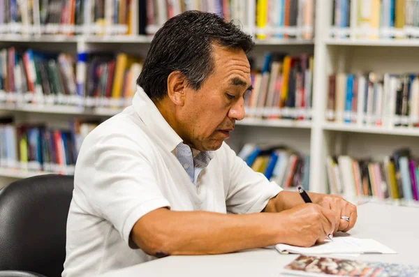 Kütüphanede not defterine yazan kıdemli adam