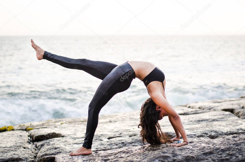 Beautiful young woman practices back yoga asana Urdhva Dhanurasana