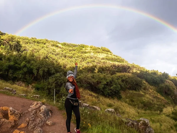 Segue o teu conceito de sonho. Uma mulher caminhando ao longo do caminho para a montanha e olhando arco-íris no céu . — Fotografia de Stock