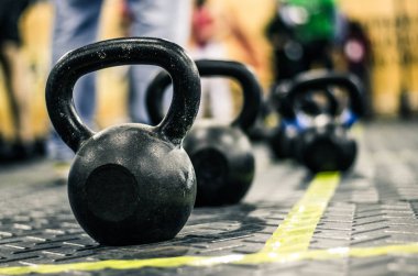 Spor salonunda yerde yatarken kettlebells ağırlıkları farklı boyutlarda.