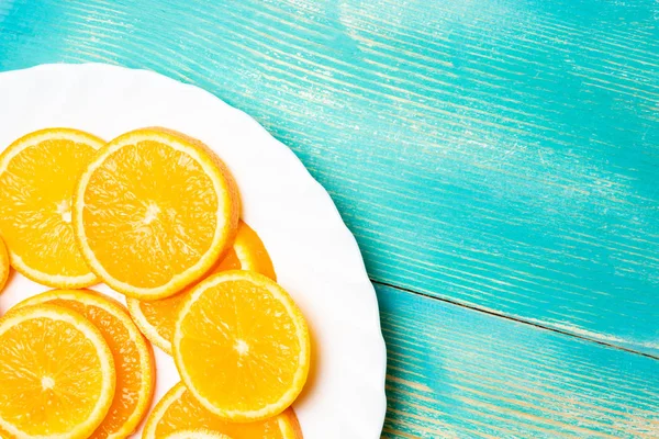 bir çerçeve, mavi arka plan köşesinde beyaz tabakta parçalar halinde kesilmiş portakal