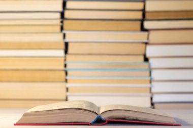 Pek çok kitap fonunda ciltli mavi açık bir kitap yığınları içinde kitap renkli bir arka plan yığılmış.