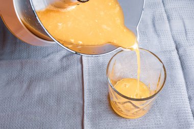 suyu bir gri kumaş zemin üzerine pişmiş bir bardak portakal suyu dökülür