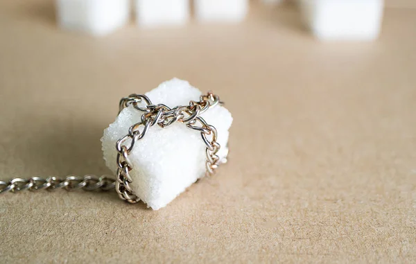 chain and sugar, the metal chain envelops the sugar against the background of other pieces